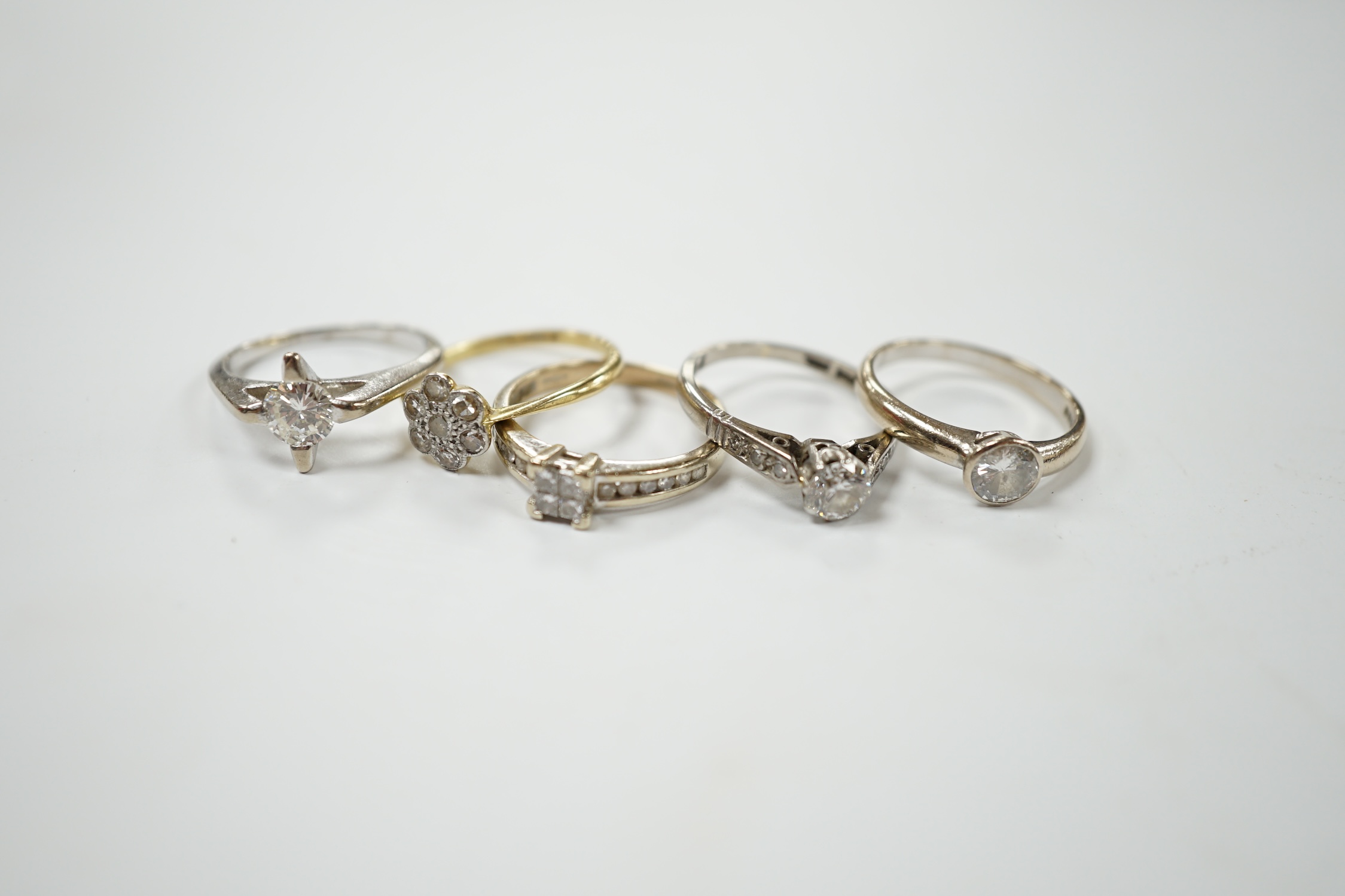 Four assorted 18ct, plat and diamond rings, including two solitaires and a flower head cluster, together with a modern 9ct and diamond cluster ring. Condition - fair